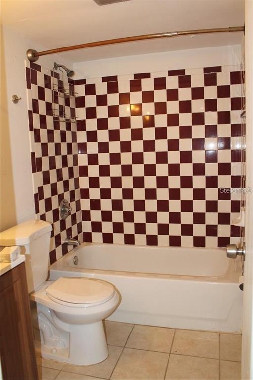 A bathroom features a white toilet and a bathtub with a maroon and white checkered wall — 3832 N LAKE DRIVE UNIT 116, TAMPA, FL