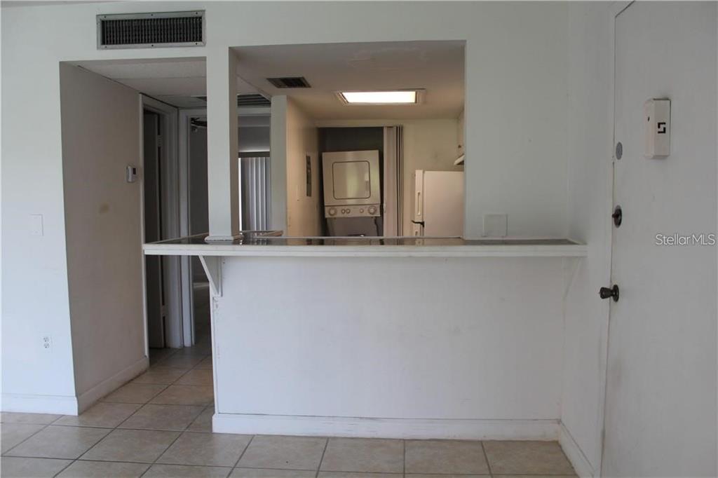 A kitchen pass-through window overlooks a tiled living area with a white breakfast bar — 3832 N LAKE DRIVE UNIT 116, TAMPA, FL