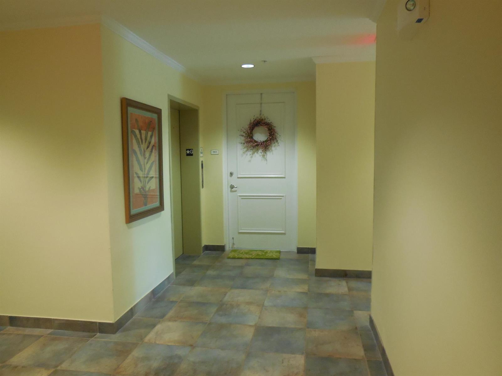 A hallway with yellow walls, tile flooring, a framed picture, and a white door — 800 Juno Ocean Walk # 302a, Juno Beach FL 33408, JUNO BEACH, FL