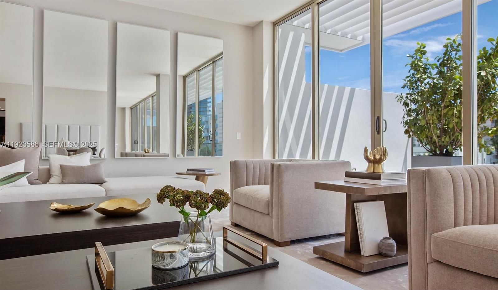 A modern living room features neutral furniture, large wall mirrors, and floor-to-ceiling windows — 300 Collins Ave, Miami Beach FL 33139, MIAMI BEACH, FL