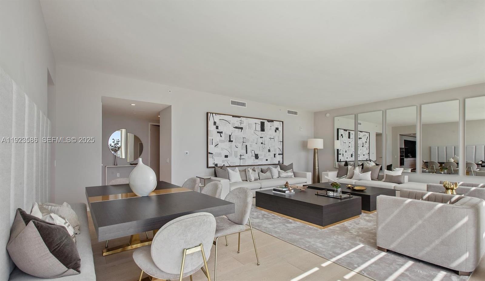 A modern living and dining room features neutral furniture, large abstract art, and mirrored walls — 300 Collins Ave, Miami Beach FL 33139, MIAMI BEACH, FL