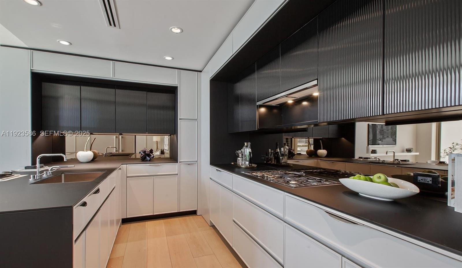 A modern kitchen features white lower cabinets, black countertops, and dark ribbed upper cabinetry — 300 Collins Ave, Miami Beach FL 33139, MIAMI BEACH, FL