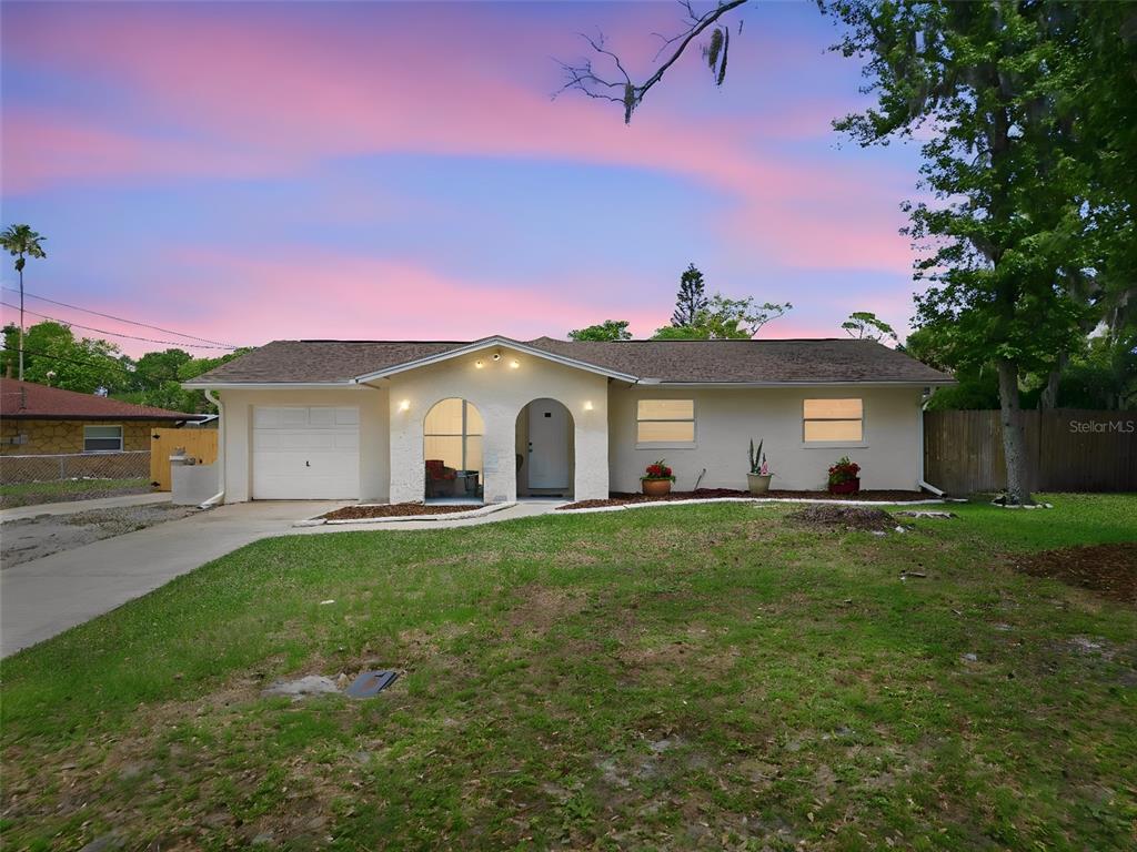 A single-story house with a white stucco exterior, arched entryway, and a one-car garage — 2861 W OAK LEA DRIVE, SOUTH DAYTONA, FL