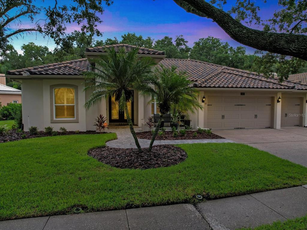 A single-story house with a tiled roof, a three-car garage, and a landscaped front yard — 4987 CROSS POINTE DRIVE, OLDSMAR, FL