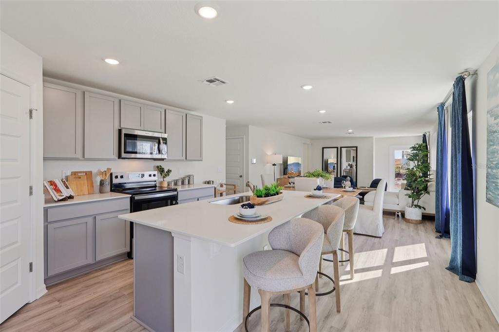 A modern kitchen with gray cabinets, a white quartz island, and bar seating — 5351 CLOUDBERRY AVENUE, LAKELAND, FL