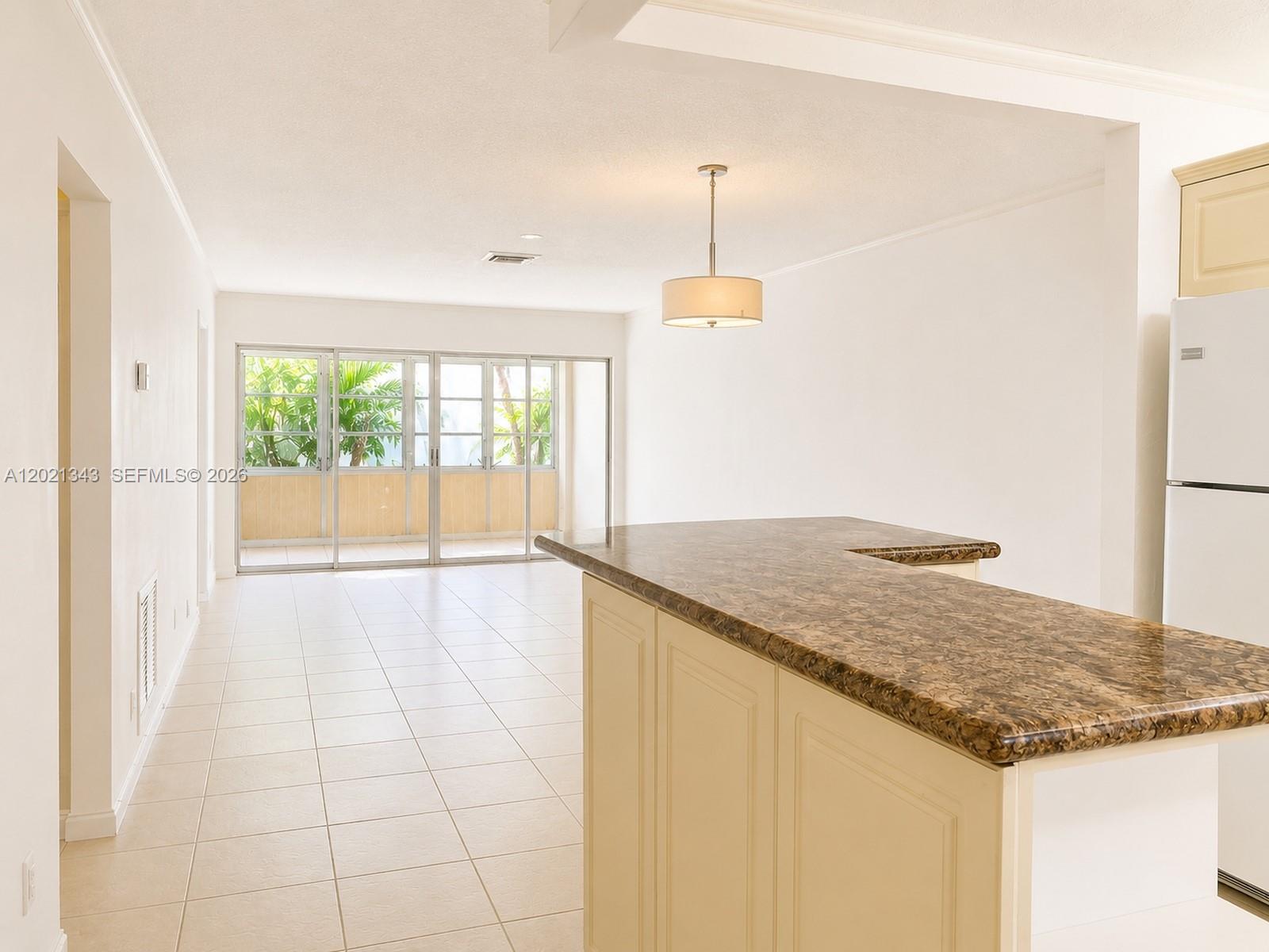An open-concept kitchen with a granite island overlooks a living area with sliding glass doors — 2832 Fillmore St # 22, Hollywood FL 33020, HOLLYWOOD, FL