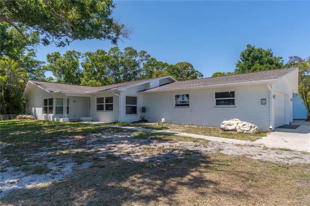 A single-story white brick house with a dark shingled roof and a concrete driveway — 12705 PARK BOULEVARD, SEMINOLE, FL
