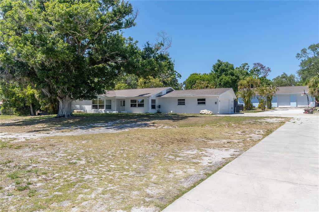A white single-story house with a large tree and a concrete driveway in front — 12705 PARK BOULEVARD, SEMINOLE, FL