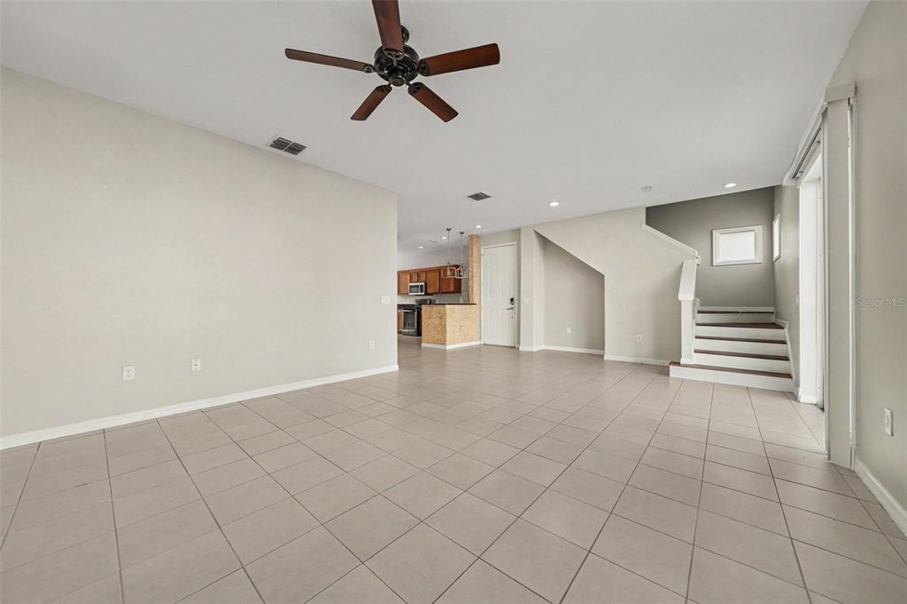 An open-concept living area features light tile flooring, a ceiling fan, and a staircase — 3606 SANCTUARY DRIVE, ST CLOUD, FL