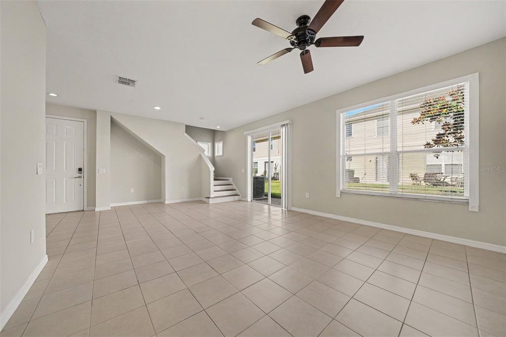 An open living area features light tile flooring, a ceiling fan, and a staircase — 3606 SANCTUARY DRIVE, ST CLOUD, FL