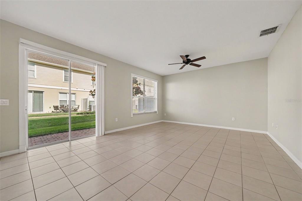 An empty room features light-colored tile flooring, a ceiling fan, and a sliding glass door — 3606 SANCTUARY DRIVE, ST CLOUD, FL
