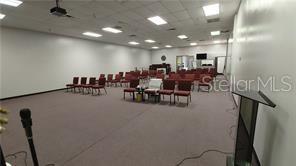 A large, carpeted meeting room features rows of red chairs and a podium — 2921 S ORLANDO DRIVE UNIT 178, SANFORD, FL