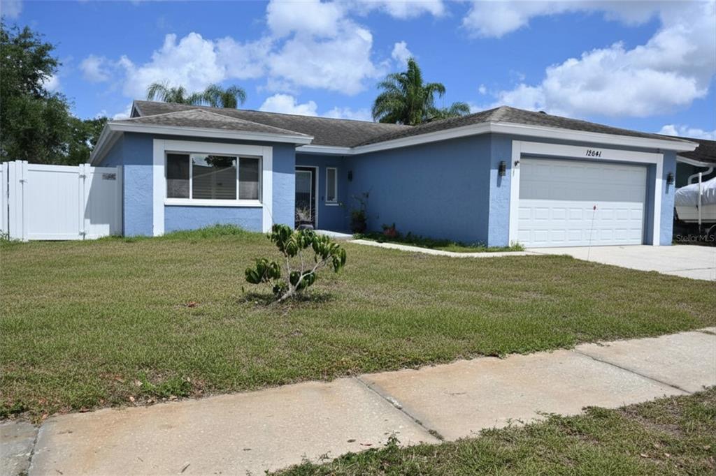 A blue single-story house with a white garage door and a white vinyl fence — 12041 70TH STREET, LARGO, FL