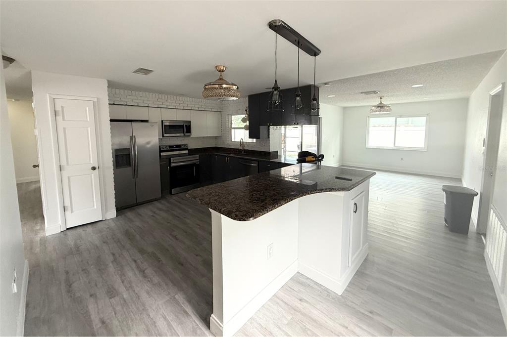 A kitchen with dark cabinets, stainless steel appliances, and a granite-topped peninsula island — 12041 70TH STREET, LARGO, FL