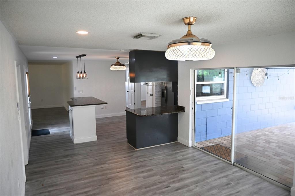 An interior view of a kitchen and dining area with dark cabinets and wood flooring — 12041 70TH STREET, LARGO, FL