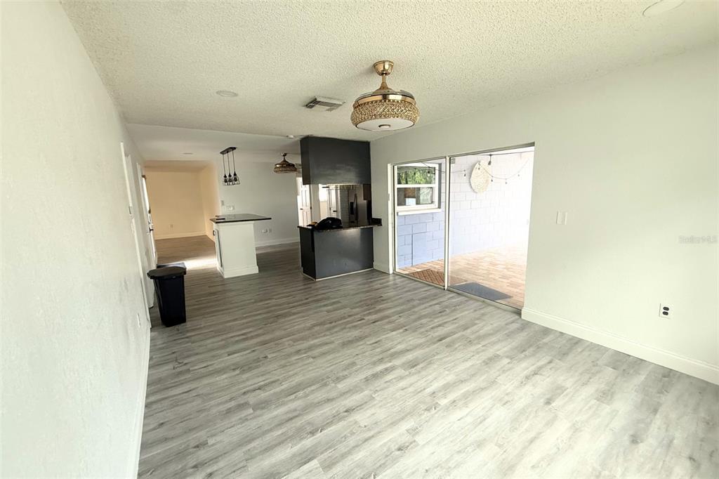 An open-concept living area with gray wood-look flooring, a kitchen island, and sliding glass doors — 12041 70TH STREET, LARGO, FL