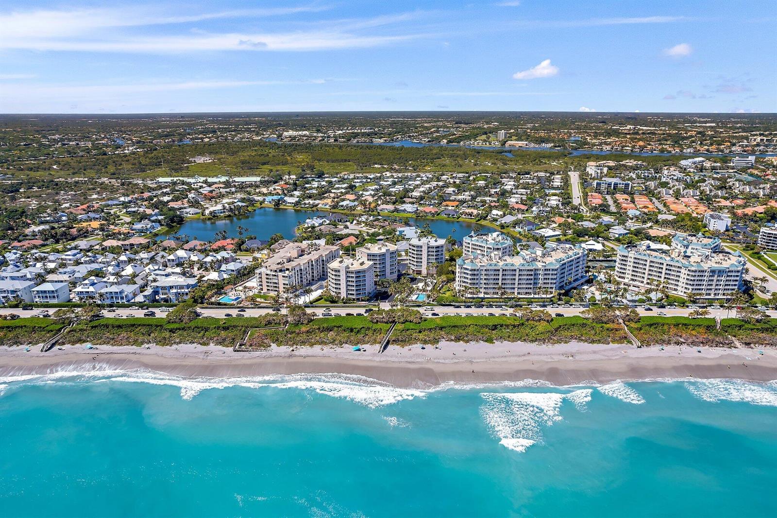 An aerial view of a coastal residential area with beachfront condominiums, a lake, and houses — 1660 S Highway A1a # 122, Jupiter FL 33477, JUPITER, FL