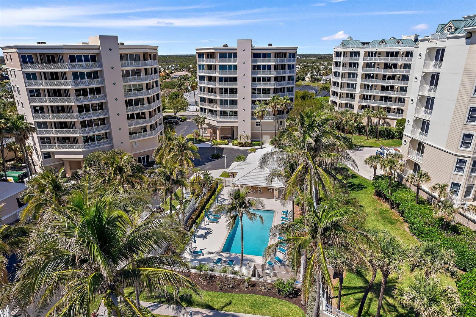 An aerial view of a swimming pool surrounded by palm trees and three multi-story buildings — 1660 S Highway A1a # 122, Jupiter FL 33477, JUPITER, FL