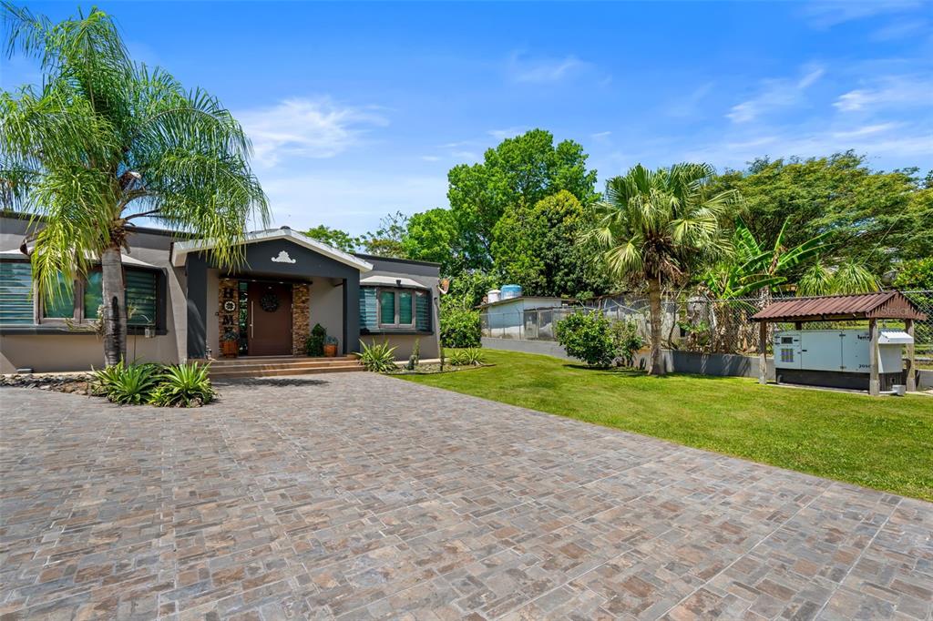 A paved driveway leads to a house with a covered entryway and a detached generator — Carr 189 Km 16.9 BO CEIBA SUR, JUNCOS, PR