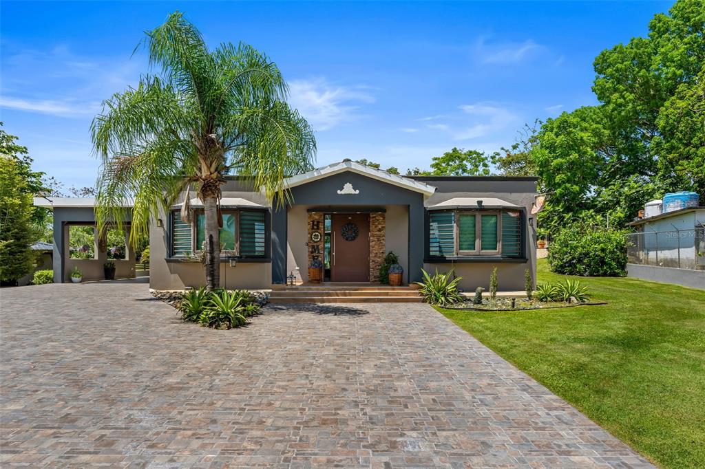 A single-story house with a paved driveway, a palm tree, and a brown front door — Carr 189 Km 16.9 BO CEIBA SUR, JUNCOS, PR