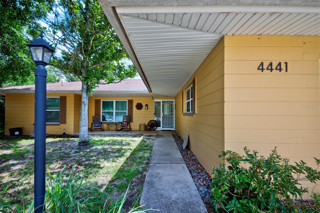 A yellow house exterior features a covered walkway leading to the front entrance — 4441 CHAMBER COURT, SPRING HILL, FL