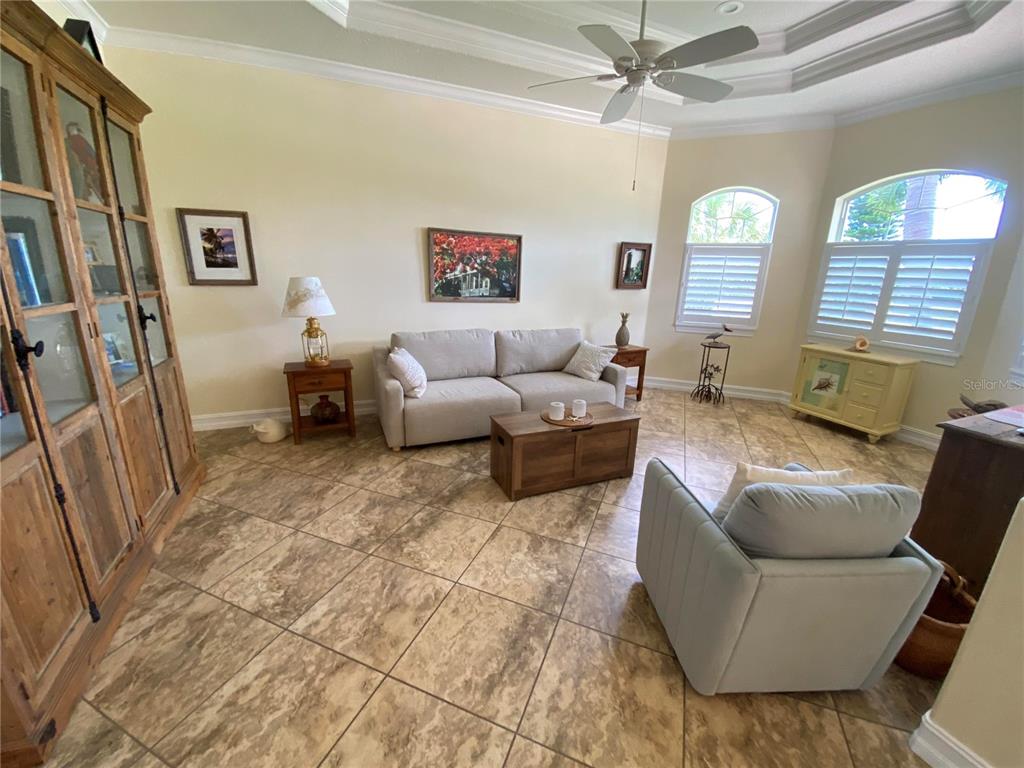 A living room features tile flooring, a beige sofa, an armchair, and a wooden cabinet — 58 TEE VIEW ROAD, ROTONDA WEST, FL