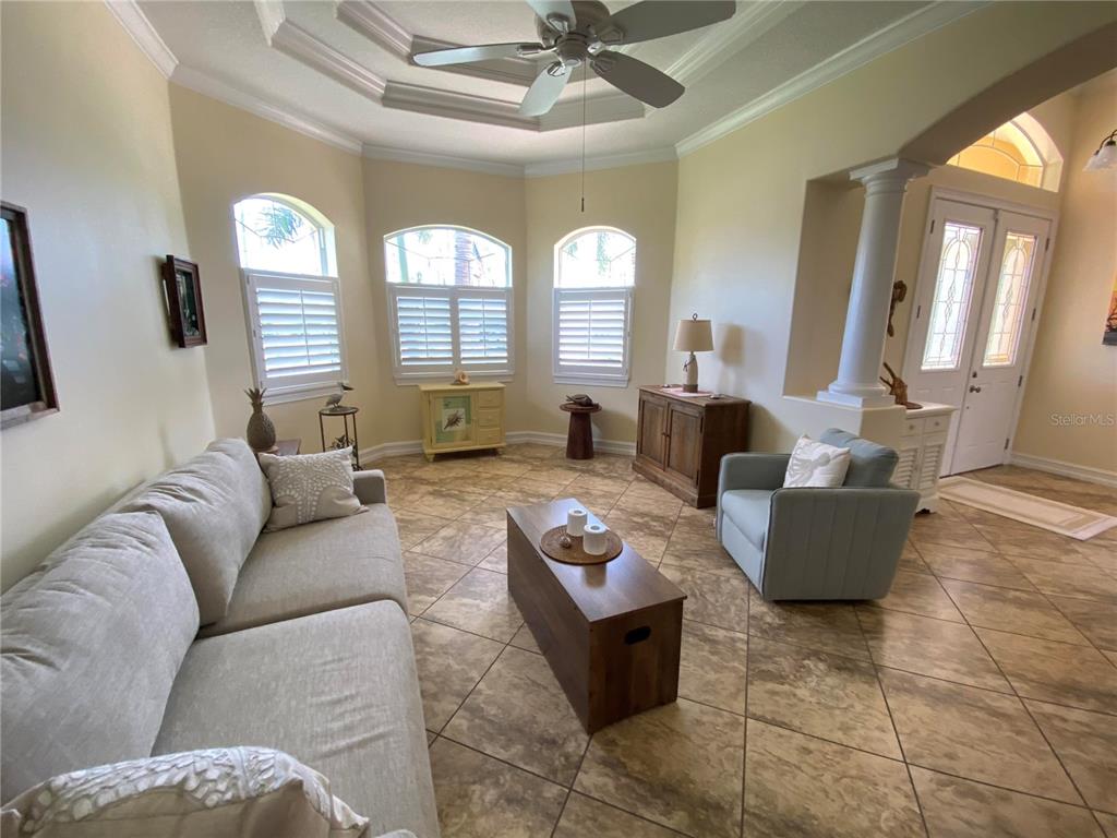 A living room features tile flooring, a tray ceiling with a fan, and three windows — 58 TEE VIEW ROAD, ROTONDA WEST, FL