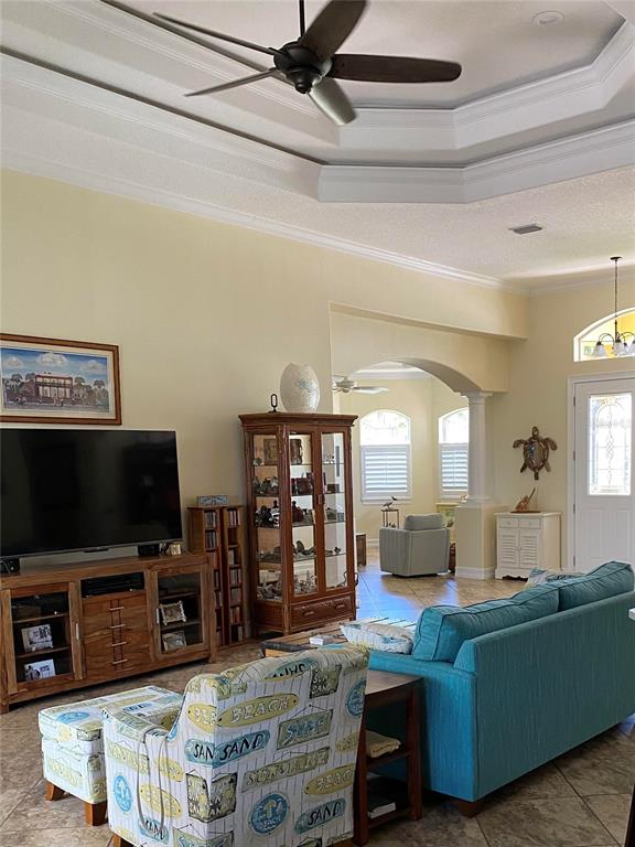 A living room features a tray ceiling, a teal sofa, and a patterned armchair — 58 TEE VIEW ROAD, ROTONDA WEST, FL