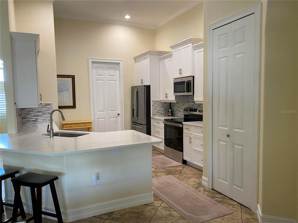 A kitchen features white cabinets, stainless steel appliances, a breakfast bar, and tile flooring — 58 TEE VIEW ROAD, ROTONDA WEST, FL