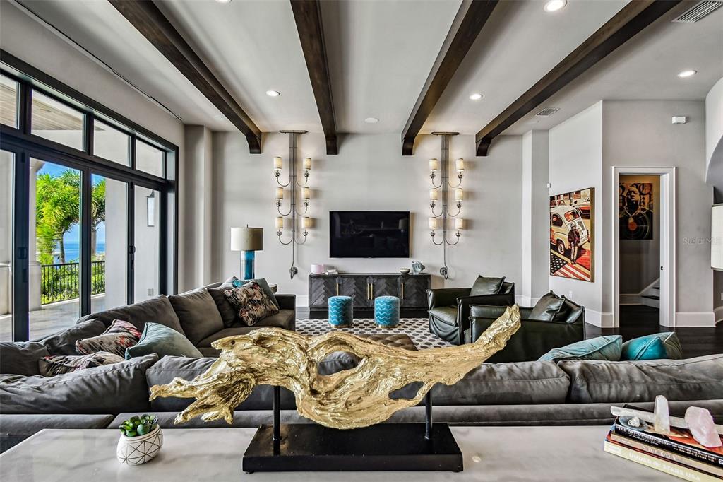 A living room features dark wood ceiling beams, a large sectional, and a gold sculpture — 5120 W LONGFELLOW AVENUE, TAMPA, FL