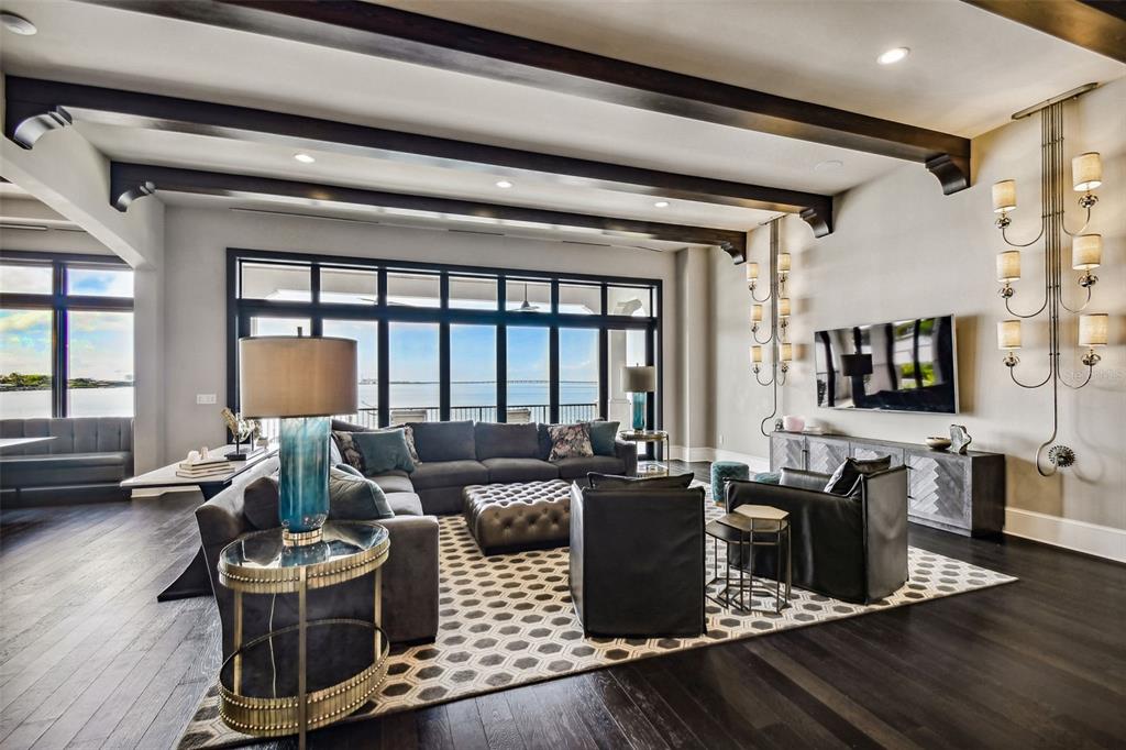 A living room features dark wood floors, exposed ceiling beams, and a large wall-mounted television — 5120 W LONGFELLOW AVENUE, TAMPA, FL
