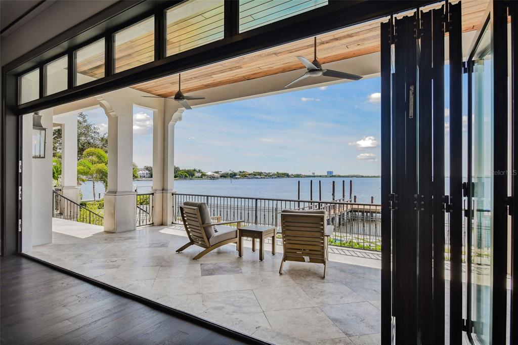 A covered patio with stone flooring overlooks a lake and a private boat dock — 5120 W LONGFELLOW AVENUE, TAMPA, FL