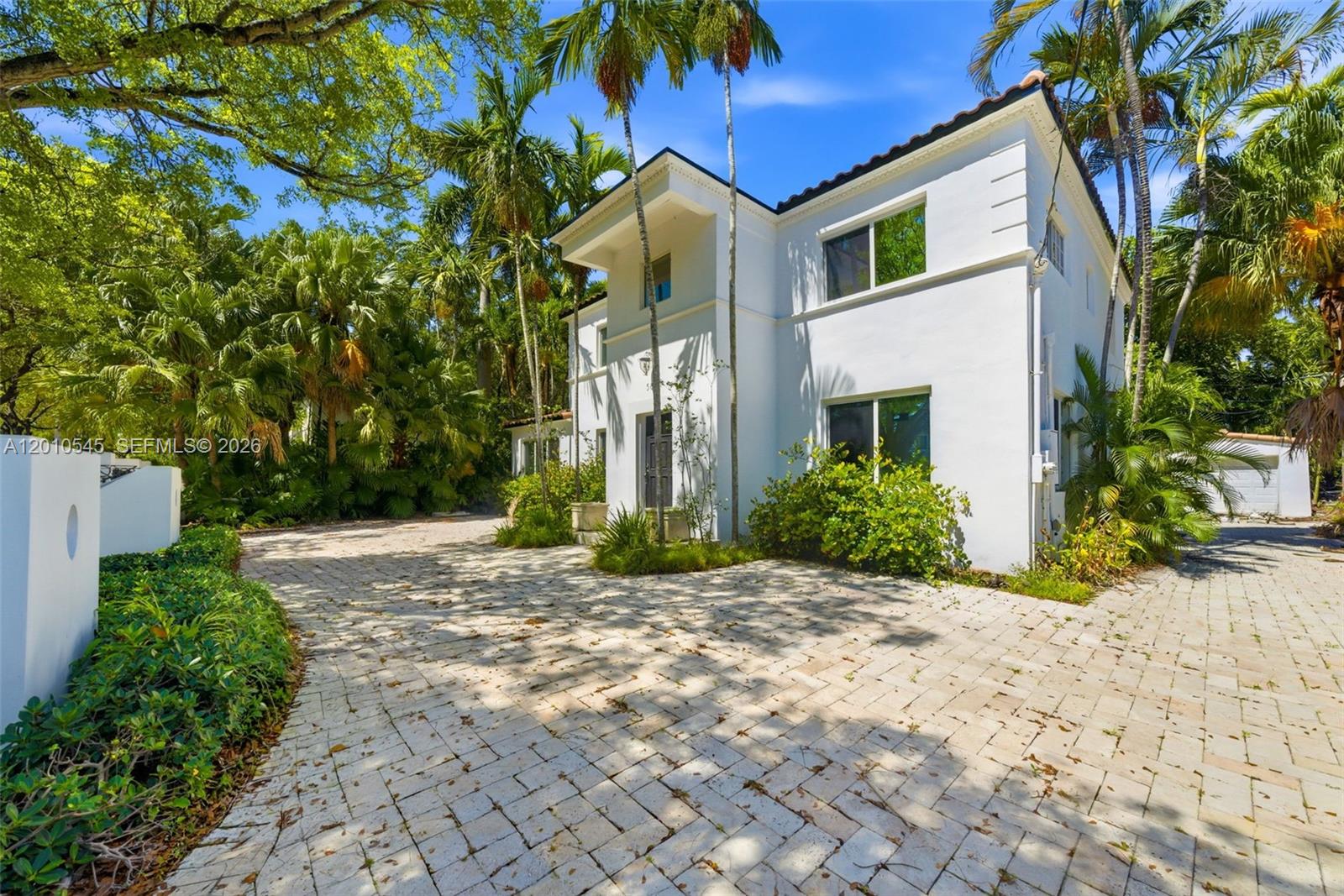 A two-story white house with a paved driveway is surrounded by lush tropical landscaping — 5824 Alton Rd, Miami Beach FL 33140, MIAMI BEACH, FL