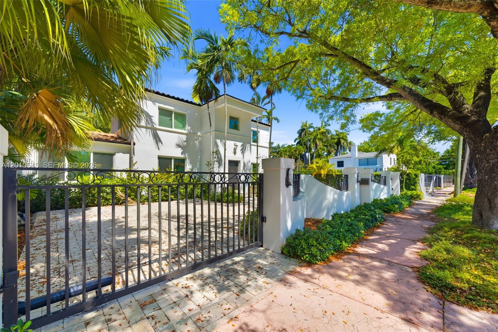 A white two-story house sits behind a metal gate and a low perimeter wall — 5824 Alton Rd, Miami Beach FL 33140, MIAMI BEACH, FL