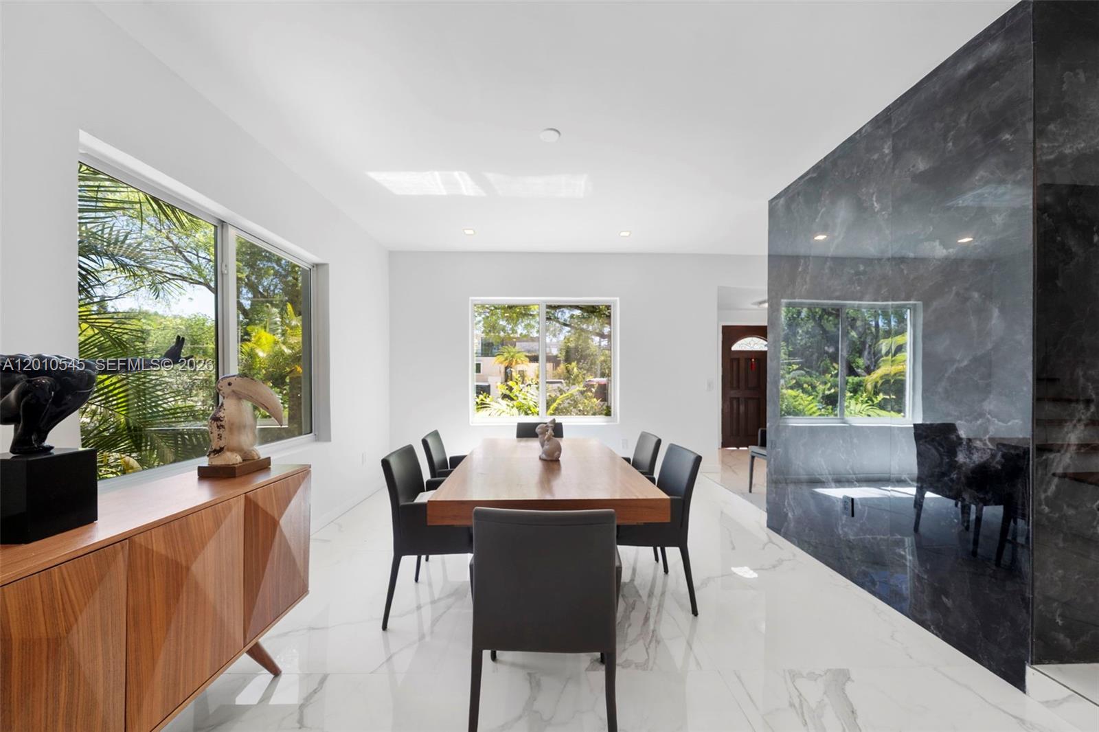 A dining room features a wooden table, dark chairs, white marble floors, and a dark accent wall — 5824 Alton Rd, Miami Beach FL 33140, MIAMI BEACH, FL