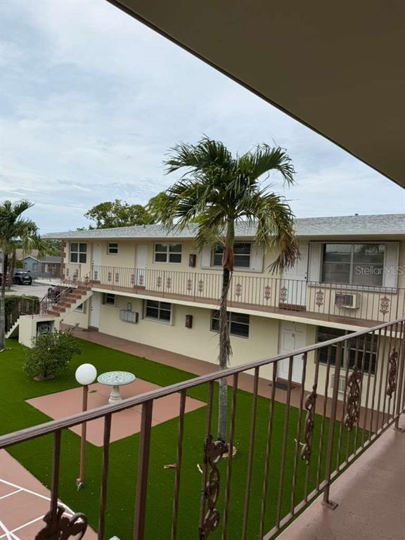 An exterior view of a two-story apartment building with a palm tree and courtyard — 1710 MCKINLEY STREET UNIT 16, HOLLYWOOD, FL