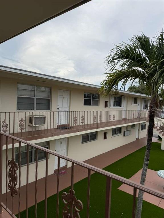 An exterior view of a two-story apartment building with a balcony and a palm tree — 1710 MCKINLEY STREET UNIT 16, HOLLYWOOD, FL