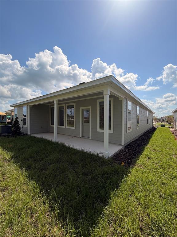 The exterior of a light gray house features a covered concrete patio and white columns — 5063 LOGGIA LANE UNIT A, KISSIMMEE, FL