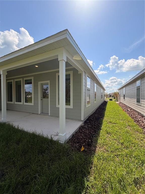 A covered concrete patio extends from the side of a light gray house — 5063 LOGGIA LANE UNIT A, KISSIMMEE, FL