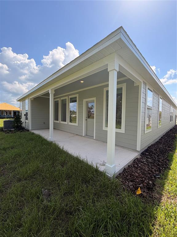 A light gray house features a covered concrete patio with white columns and trim — 5063 LOGGIA LANE UNIT A, KISSIMMEE, FL