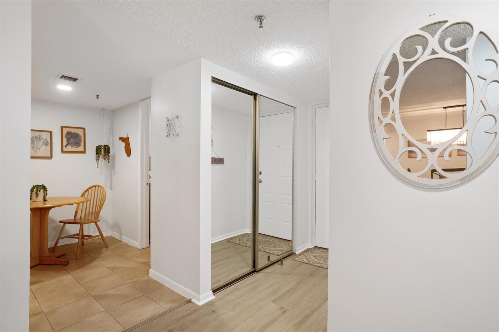 A bright entryway features a mirrored closet, light wood flooring, and a small dining area — 950 Lavers Circle # F307, Delray Beach FL 33444, DELRAY BEACH, FL