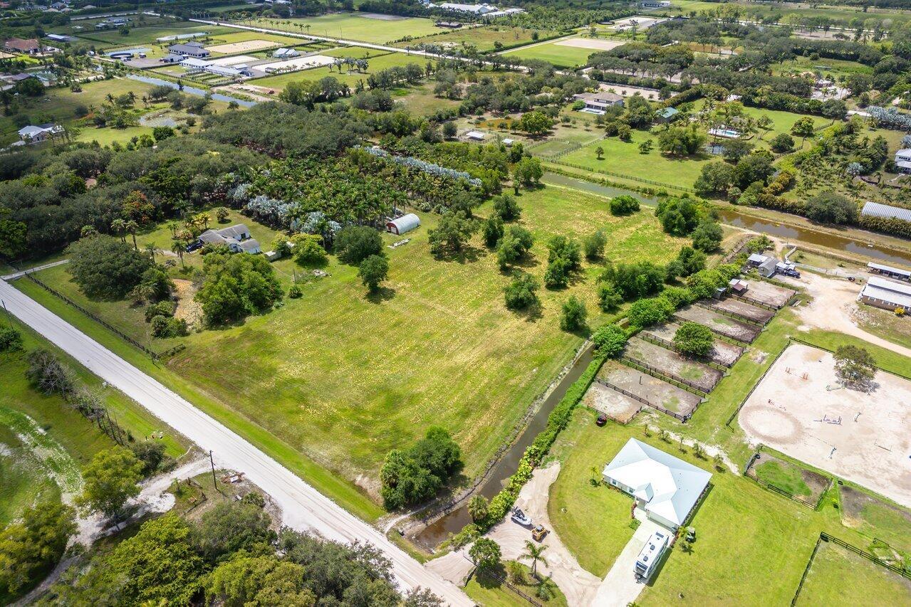An aerial view shows a rural property with a house, horse paddocks, and palm trees — 16526 Hollow Tree Lane, Wellington FL 33470, WELLINGTON, FL