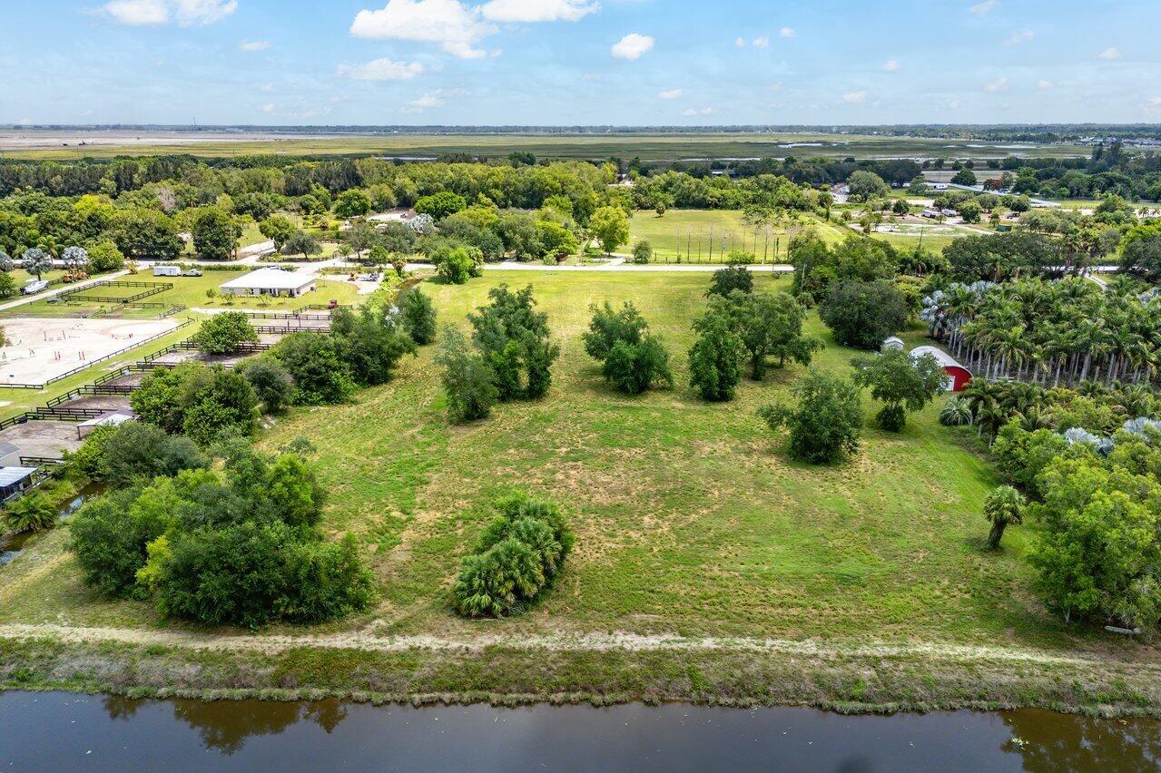 An aerial view shows a large, grassy lot with scattered trees and a nearby pond — 16526 Hollow Tree Lane, Wellington FL 33470, WELLINGTON, FL