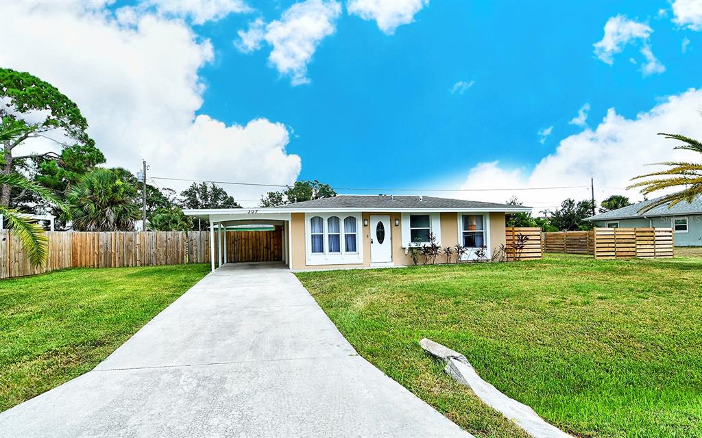 A single-story house with a carport, concrete driveway, and a fenced yard under a cloudy sky — 307 SOUTHLAND ROAD, VENICE, FL