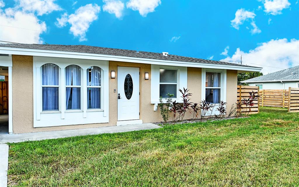 The exterior of a single-story house features a white front door and arched windows — 307 SOUTHLAND ROAD, VENICE, FL