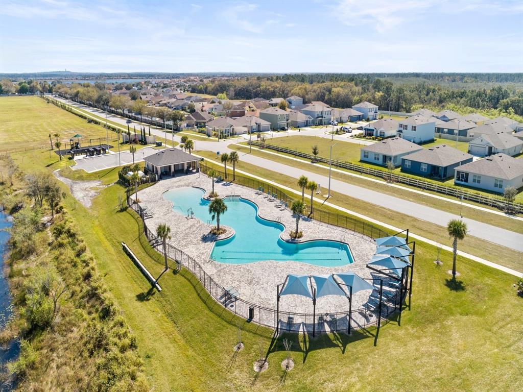 An aerial view shows a community swimming pool with a deck, cabana, and shade structures — 3968 GIORGIO DRIVE, WINTER HAVEN, FL