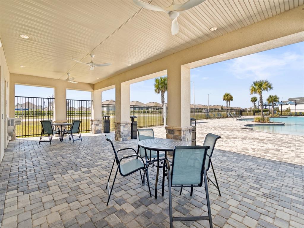 A covered patio with stone pillars, outdoor dining sets, and a view of a pool — 3968 GIORGIO DRIVE, WINTER HAVEN, FL