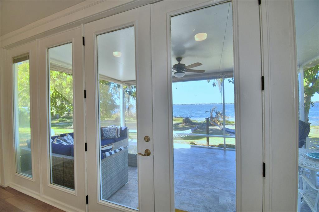 A view through glass doors looking out onto a screened porch and a lake — 1173 S LAKE REEDY BOULEVARD, FROSTPROOF, FL