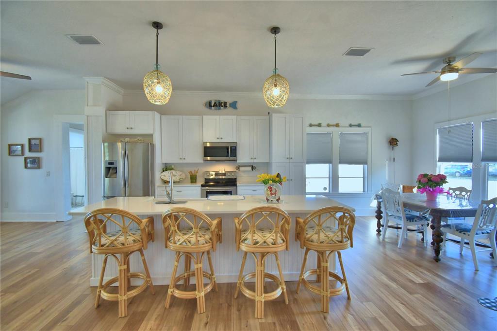 A kitchen with white cabinets, a large island with four rattan stools, and wood flooring — 1173 S LAKE REEDY BOULEVARD, FROSTPROOF, FL