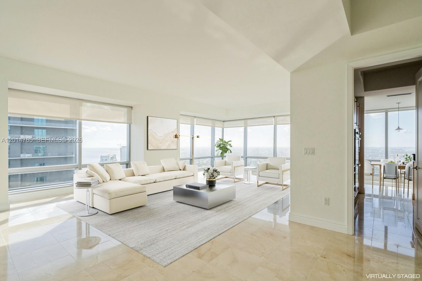 A bright, modern living room features a white sectional sofa, floor-to-ceiling windows, and marble flooring — 1425 Brickell Ave # 57B, Miami FL 33131, MIAMI, FL